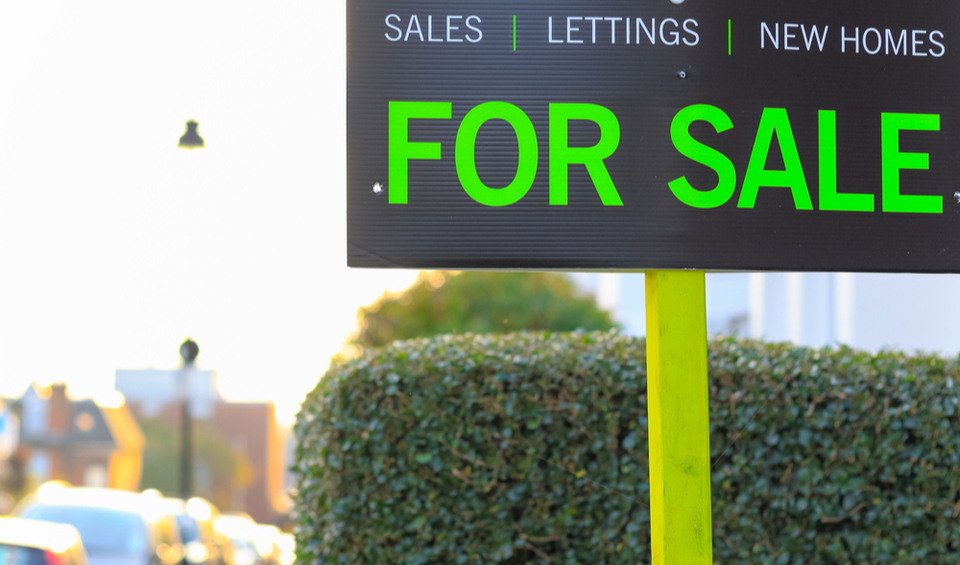 A close-up of a “For sale” sign outside of a home.