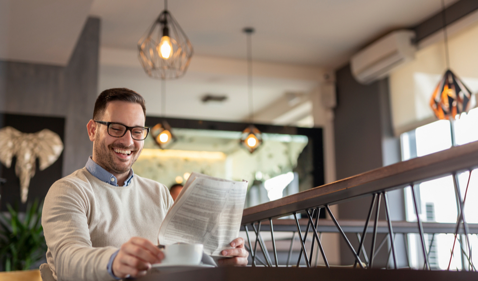 A man reading a newspaper while drinking coffee, illustrating an article about the new tax year