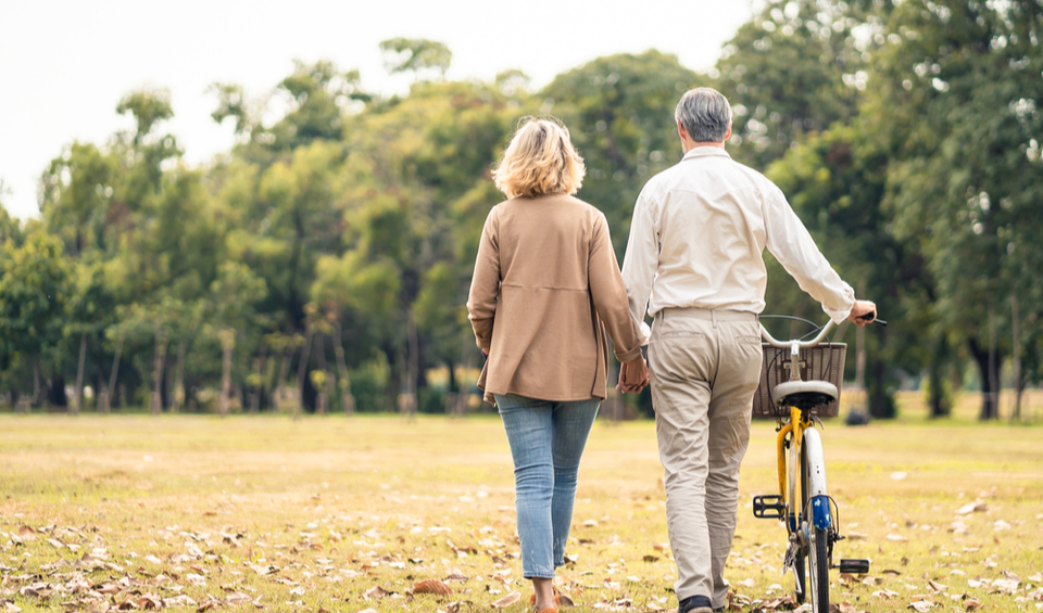 A couple walking through a park and pushing a bike illustrating an article on estate planning
