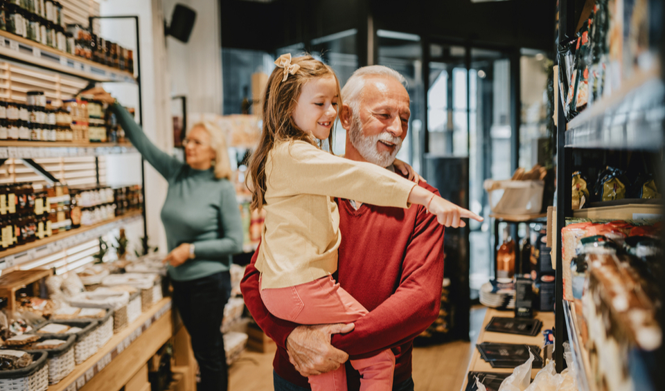 A grandfather grocery shopping with his granddaughter, illustrating an article about retirement costs